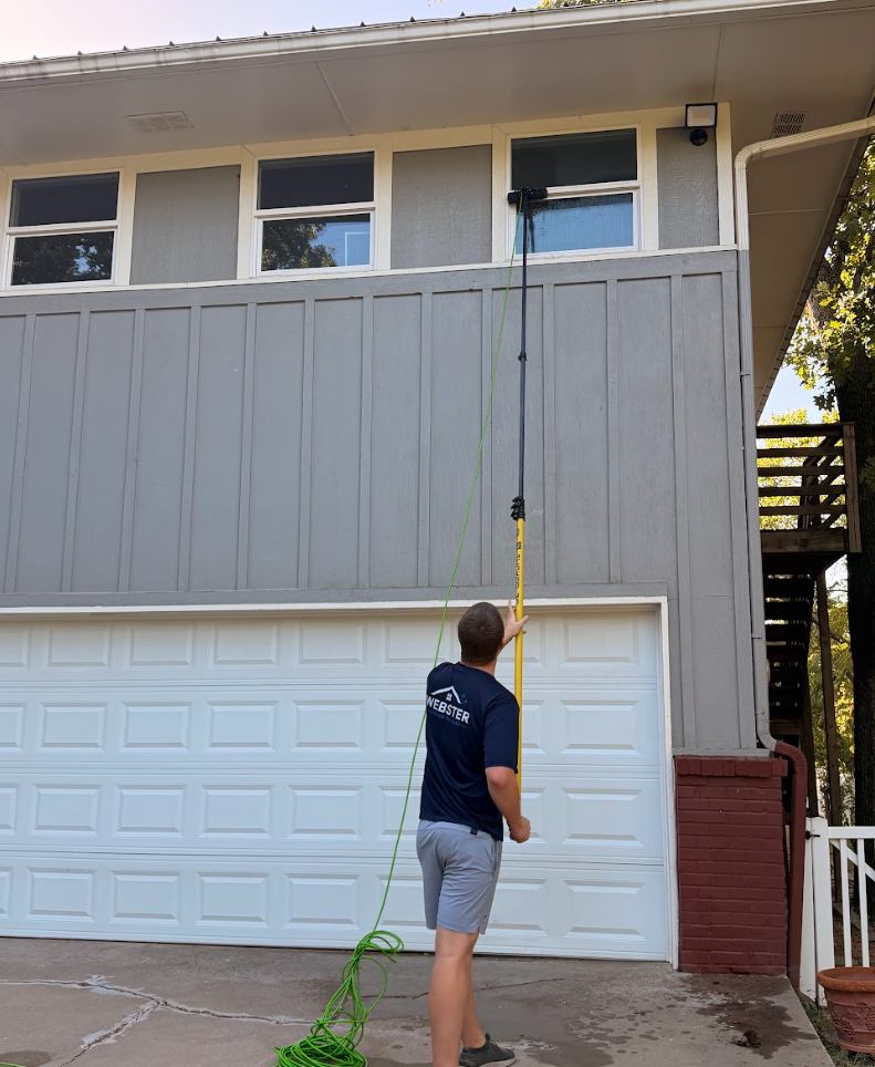 Webster Exterior Cleaning technician spraying and rinsing a second-story window with a water-fed pole