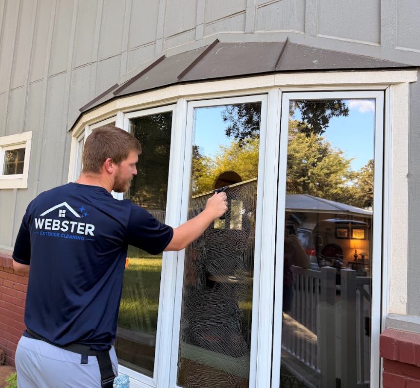 Webster Exterior Cleaning technician hand-squeegeeing a bay window